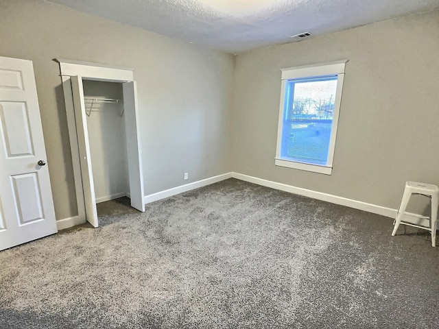 unfurnished bedroom with visible vents, baseboards, a textured ceiling, carpet flooring, and a closet