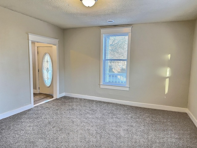 entrance foyer featuring carpet, visible vents, a textured ceiling, and baseboards