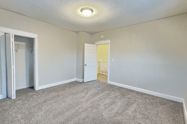 unfurnished bedroom with carpet floors, baseboards, and a textured ceiling