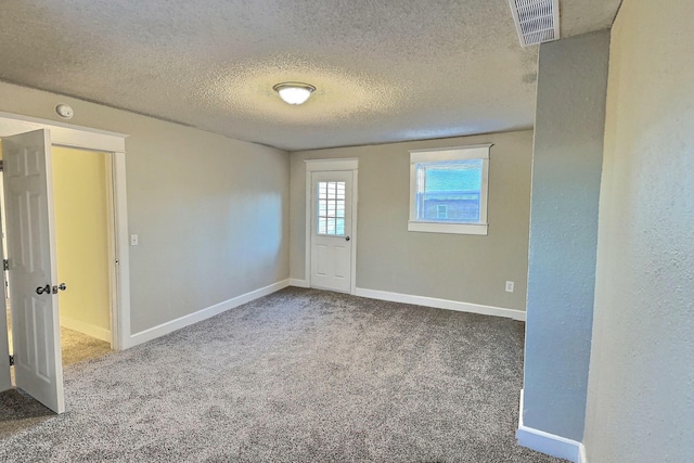 carpeted spare room featuring a textured ceiling, visible vents, and baseboards