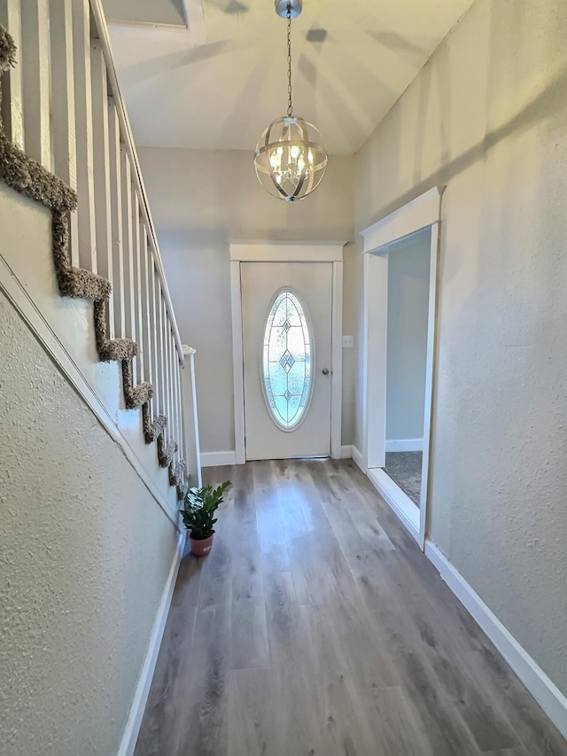 foyer entrance with a notable chandelier, baseboards, stairway, and wood finished floors