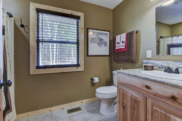 bathroom featuring toilet, vanity, baseboards, visible vents, and tile patterned floors