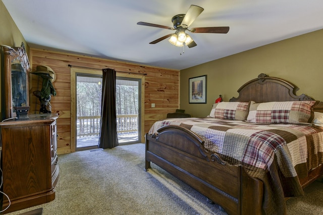 bedroom with carpet floors, access to exterior, ceiling fan, and wood walls