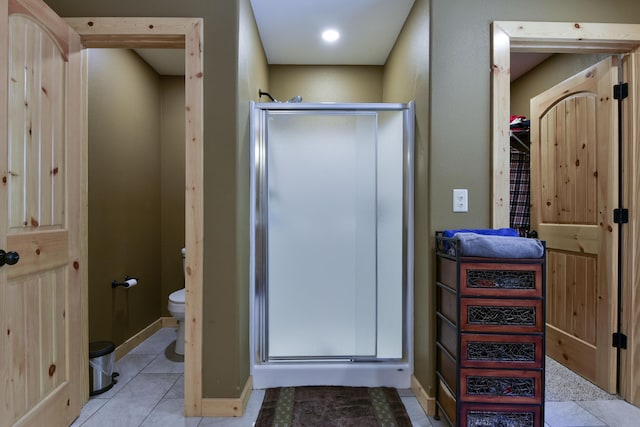 bathroom with a stall shower, baseboards, toilet, and tile patterned floors