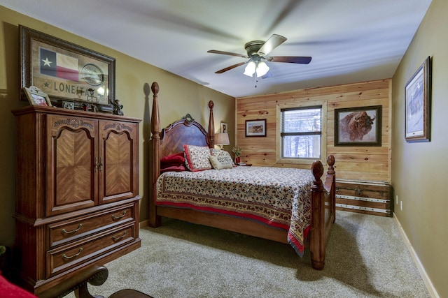 bedroom featuring light carpet, wood walls, baseboards, and a ceiling fan