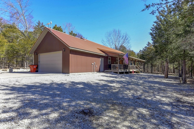 view of property exterior featuring a garage, metal roof, driveway, and a deck