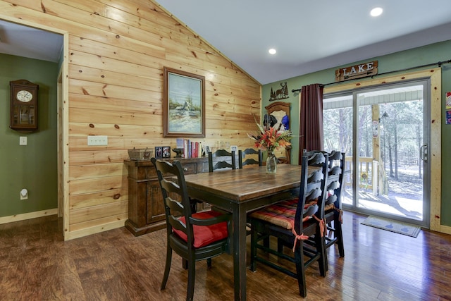 dining space with wood walls, baseboards, vaulted ceiling, and dark wood-type flooring