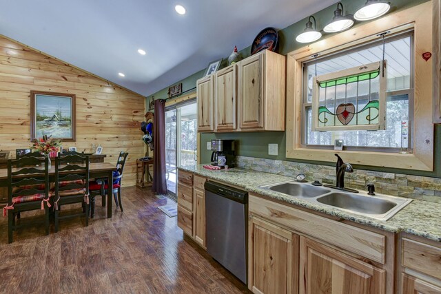 kitchen featuring dark wood-type flooring, vaulted ceiling, stainless steel dishwasher, light brown cabinets, and a sink