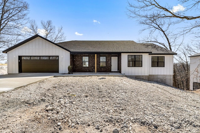 view of front facade with board and batten siding, concrete driveway, an attached garage, and roof with shingles