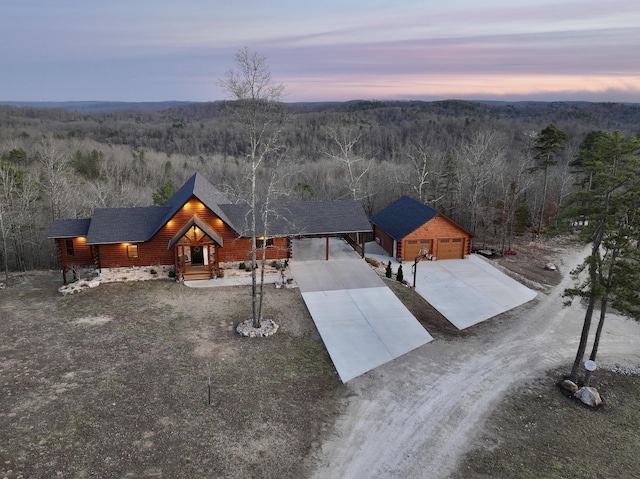 aerial view at dusk featuring a wooded view