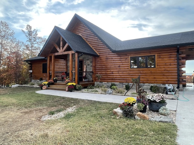 cabin featuring a porch, a front lawn, a shingled roof, and log siding