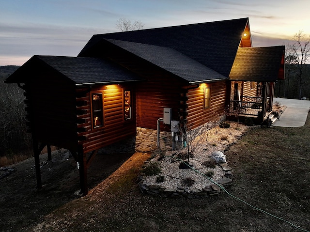 view of side of home with a shingled roof and log siding