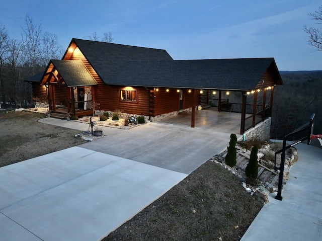 cabin featuring driveway and roof with shingles