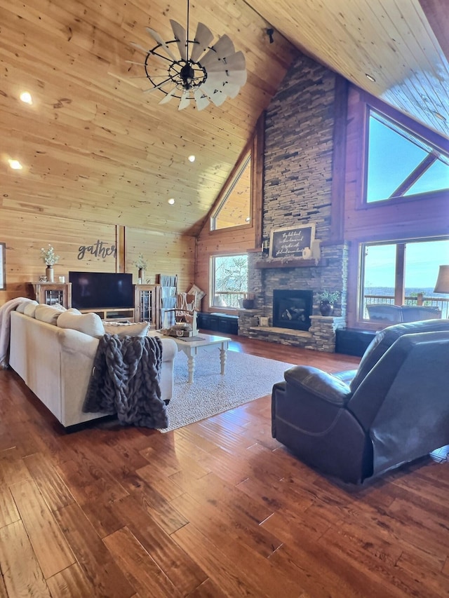 living area featuring wood ceiling, wooden walls, hardwood / wood-style floors, and a stone fireplace