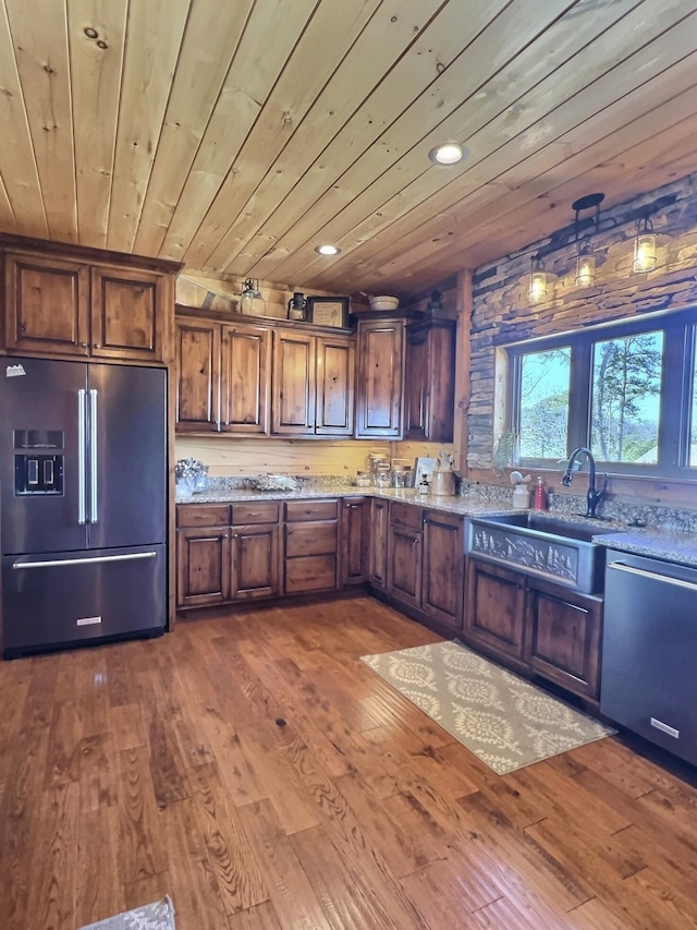 kitchen featuring high end refrigerator, a sink, wood finished floors, wood ceiling, and dishwasher