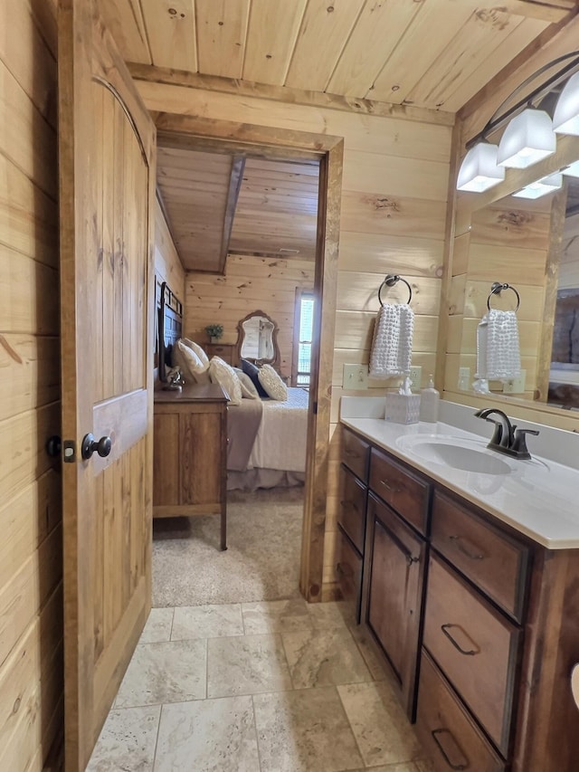 ensuite bathroom featuring stone tile floors, ensuite bathroom, wooden walls, vanity, and wooden ceiling