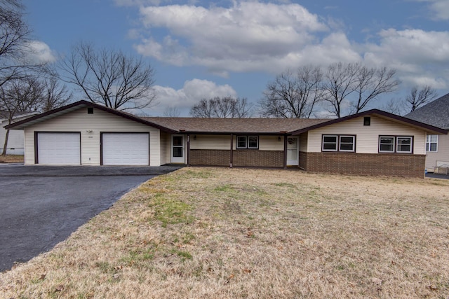 single story home with a garage, aphalt driveway, a front lawn, and brick siding