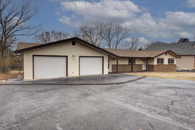 ranch-style house with aphalt driveway, a garage, a shingled roof, brick siding, and fence