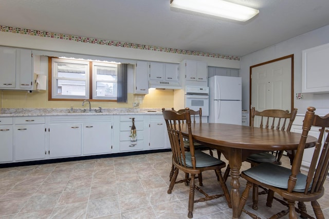 kitchen with tasteful backsplash, white appliances, a sink, and under cabinet range hood