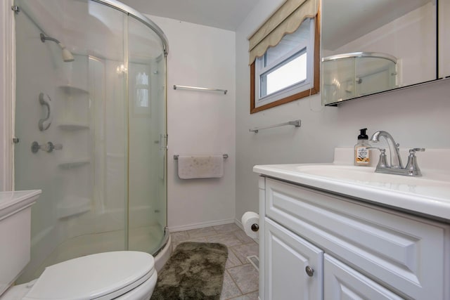 bathroom featuring toilet, a shower stall, baseboards, and vanity