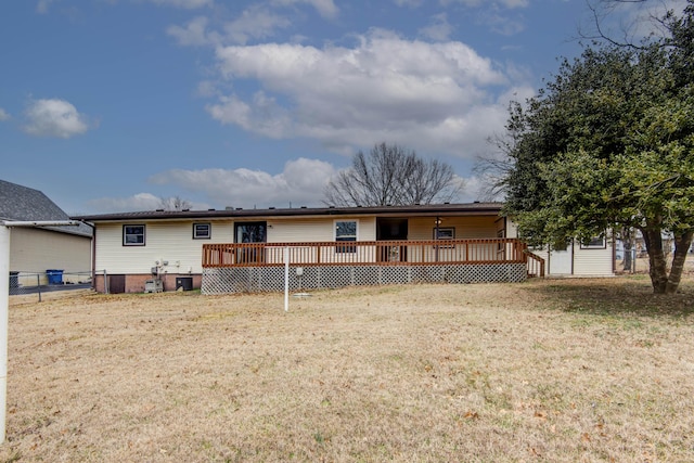 rear view of property featuring a lawn, a wooden deck, and fence