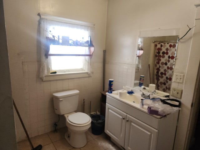 bathroom featuring toilet, a wainscoted wall, vanity, tile walls, and tile patterned floors