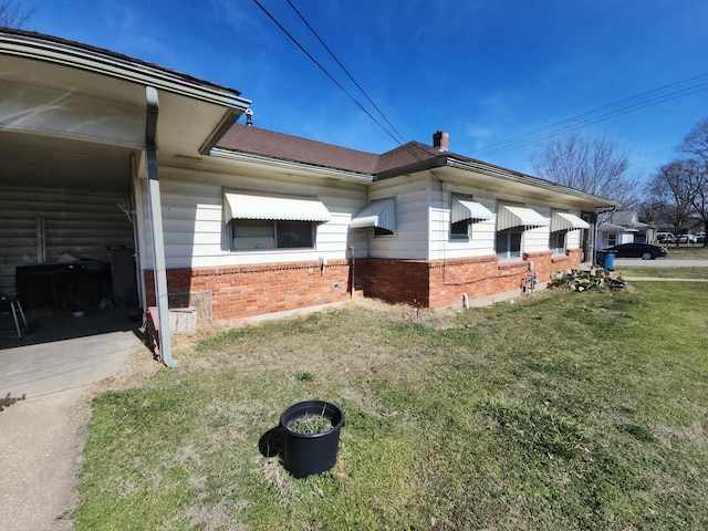 view of property exterior with brick siding, a yard, and a chimney