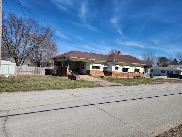 view of front of property with a front yard, brick siding, fence, and a chimney