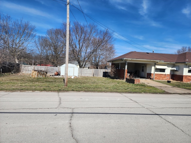 view of home's exterior with brick siding, a yard, fence, a shed, and an outdoor structure