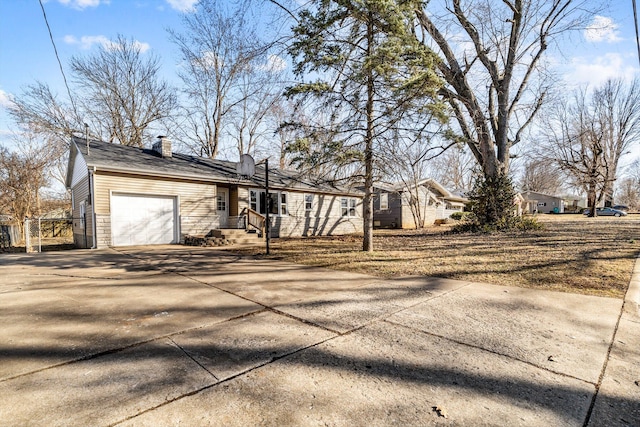 view of side of property with a garage, stone siding, driveway, and a chimney