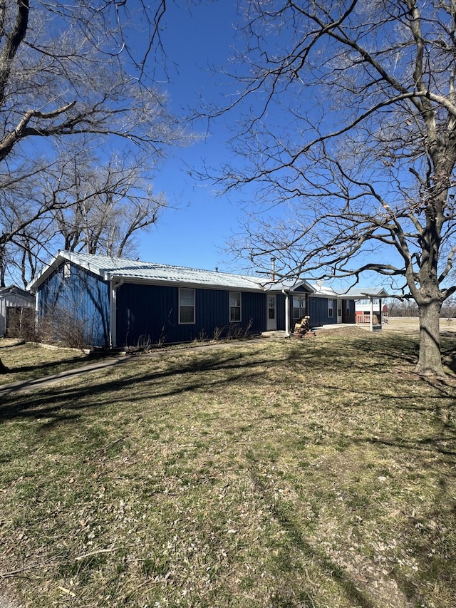 rear view of property featuring metal roof and a lawn