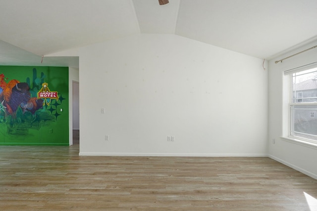 unfurnished room with light wood-style floors, vaulted ceiling, and baseboards