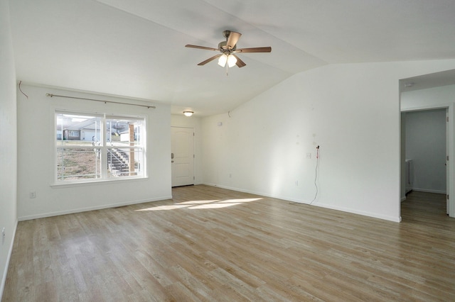 spare room featuring a ceiling fan, lofted ceiling, light wood-style flooring, and baseboards