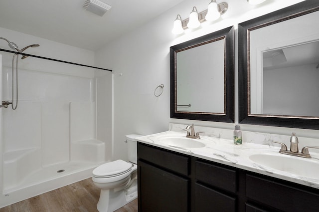 bathroom with toilet, double vanity, a sink, and visible vents