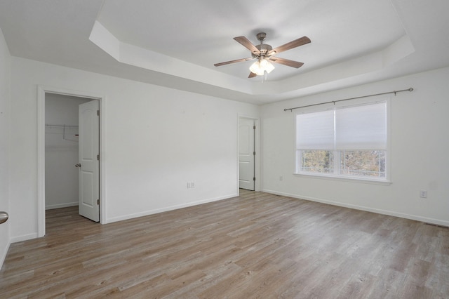 unfurnished room with a tray ceiling, baseboards, and light wood finished floors