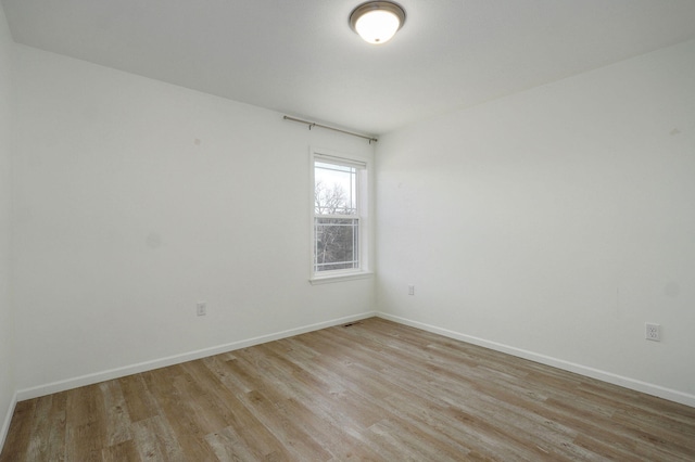 unfurnished room featuring baseboards and light wood-style floors