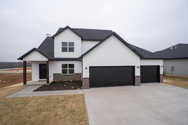 modern inspired farmhouse featuring a shingled roof, an attached garage, a front yard, stone siding, and driveway