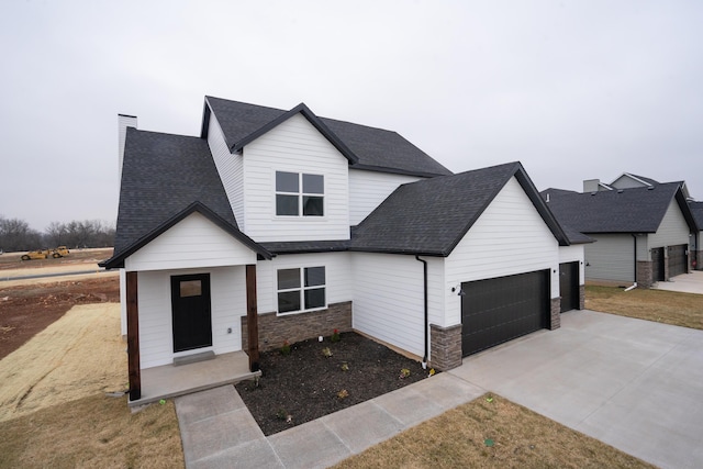 modern farmhouse style home with a chimney, a shingled roof, an attached garage, stone siding, and driveway