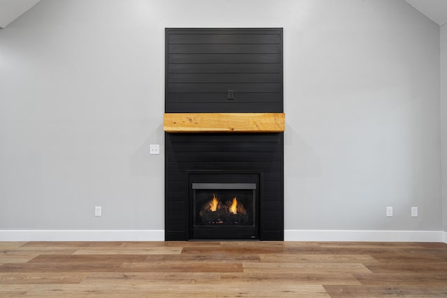 room details with a large fireplace, wood finished floors, and baseboards