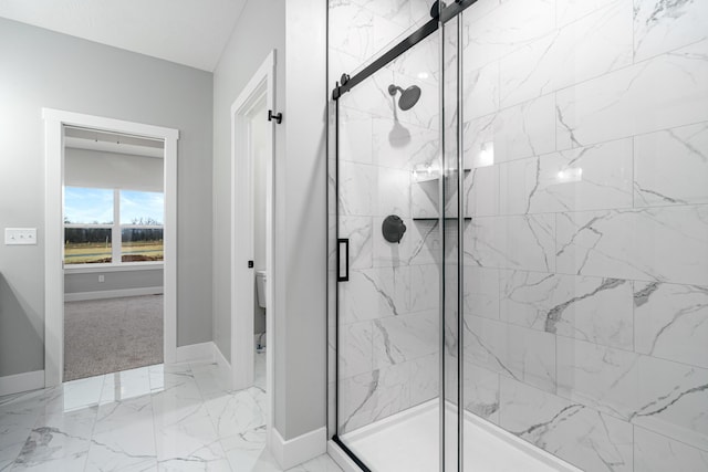 full bathroom featuring toilet, marble finish floor, a marble finish shower, and baseboards