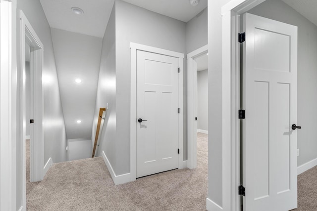 hall with baseboards, carpet flooring, and an upstairs landing