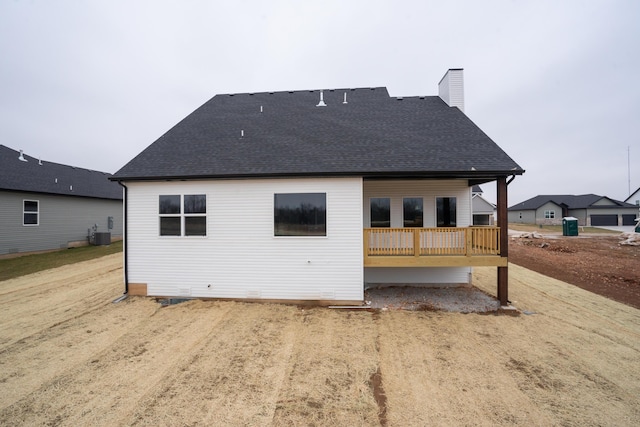 back of house featuring a shingled roof and a chimney