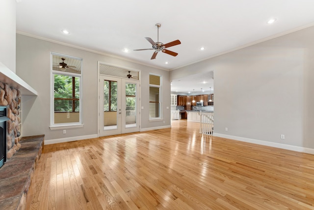 unfurnished living room featuring light wood finished floors, recessed lighting, ornamental molding, a stone fireplace, and baseboards