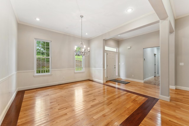 entryway with light wood finished floors, a wainscoted wall, ornamental molding, a notable chandelier, and recessed lighting