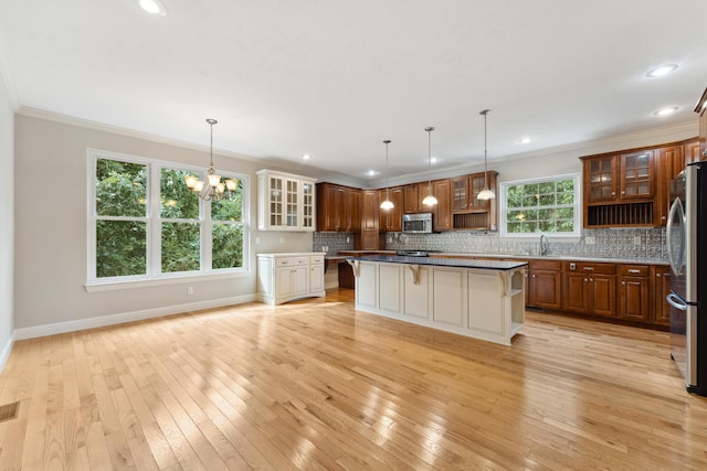 kitchen with stainless steel appliances, ornamental molding, light wood-style flooring, and a kitchen breakfast bar