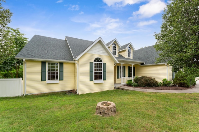 view of front of property featuring a fire pit, a front lawn, a shingled roof, and fence