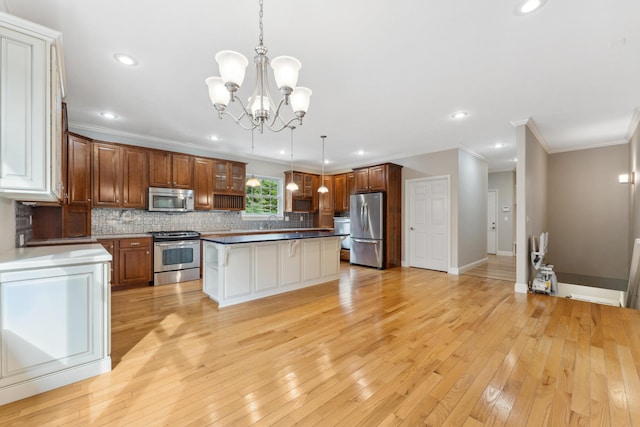 kitchen with light wood finished floors, baseboards, a kitchen island, appliances with stainless steel finishes, and backsplash