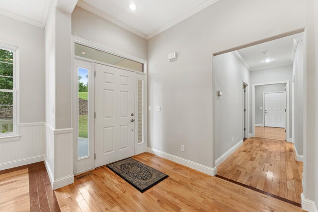 entryway featuring light wood-type flooring, baseboards, visible vents, and crown molding