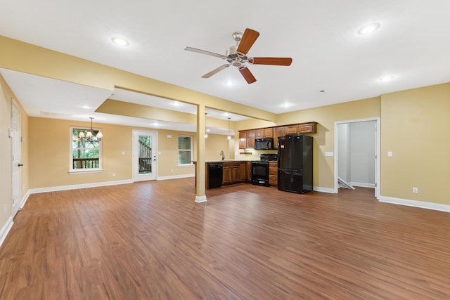 unfurnished living room featuring recessed lighting, a sink, wood finished floors, baseboards, and ceiling fan with notable chandelier