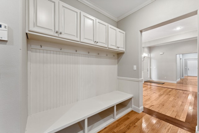 mudroom featuring ornamental molding, wainscoting, light wood-style flooring, and baseboards